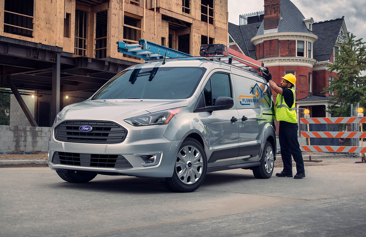 A Ford Transit Connect with Worker Using Ladder Rack.